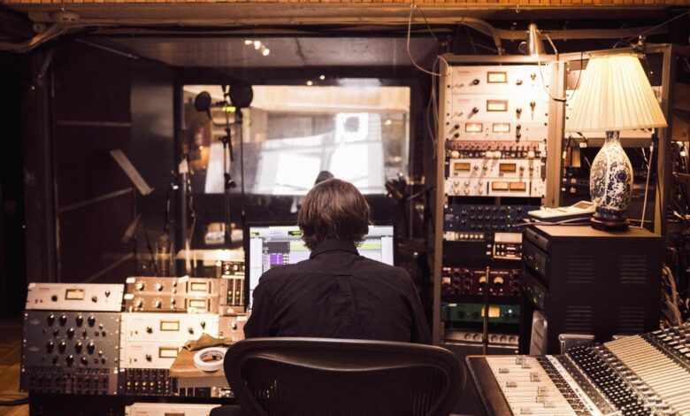 Pria di depan mixer dan penerima studio